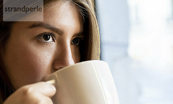 Nahaufnahme einer Frau  die beim Kaffeetrinken im Café wegschaut
