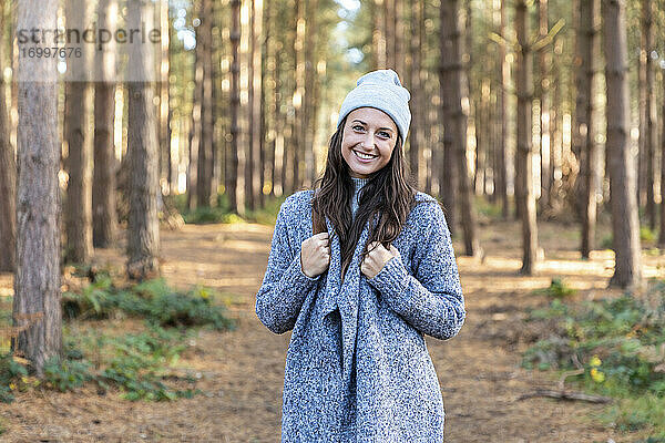 Lächelnde schöne Frau im Wald von Cannock Chase während der Wintersaison