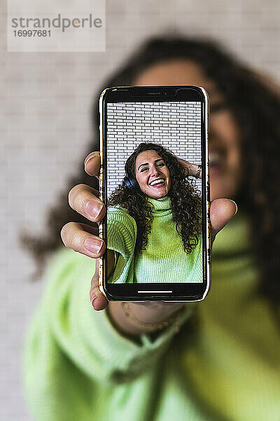 Junge Frau zeigt Foto auf Smartphone