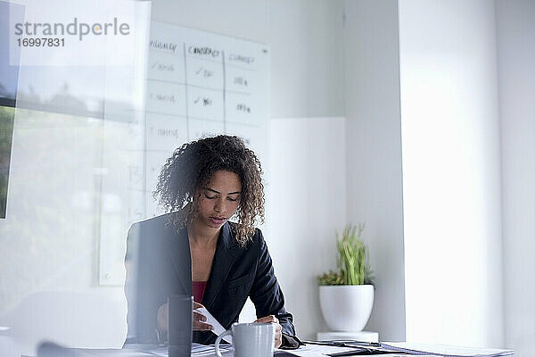 Geschäftsfrau mit Dokument auf dem Schreibtisch sitzend im Büro