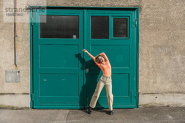 Junge Frau tanzt  während sie vor einer grünen Tür steht