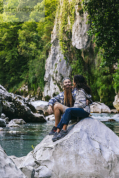 Glückliches junges Paar sitzt auf einem Felsen beim Wandern in den Picos De Europa  Asturien  Spanien