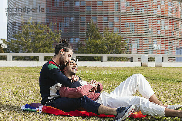 Zärtlicher Mann umarmt Partnerin beim Sitzen im Park