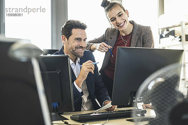 Geschäftsleute  die einen Computer benutzen  während sie im Büro zusammenarbeiten