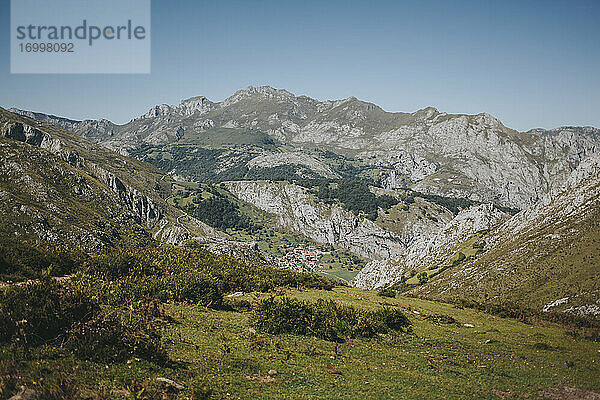 Fernblick auf das Dorf Bejes vor einer Bergkette an einem sonnigen Tag  Nationalpark Picos de Europa  Asturien  Spanien
