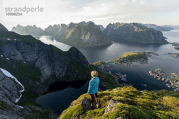 Wanderer bewundert die Aussicht  während er auf einem Berg bei Reinebringen  Lofoten  Norwegen steht