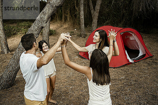 Glückliche Familie hält Hände auf dem Campingplatz im Wald während der Ferien
