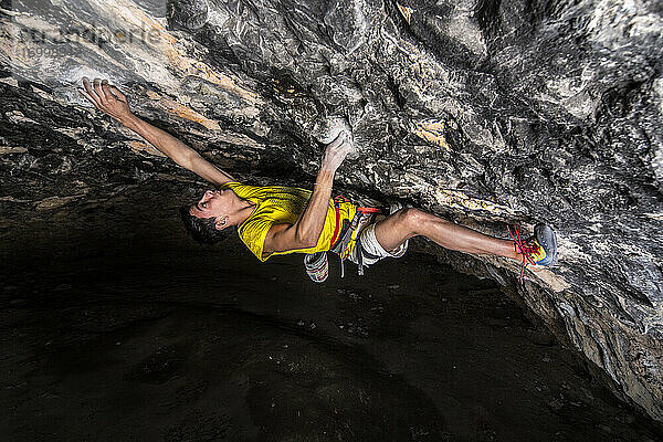 Junger Sportler beim Klettern in einer Höhle