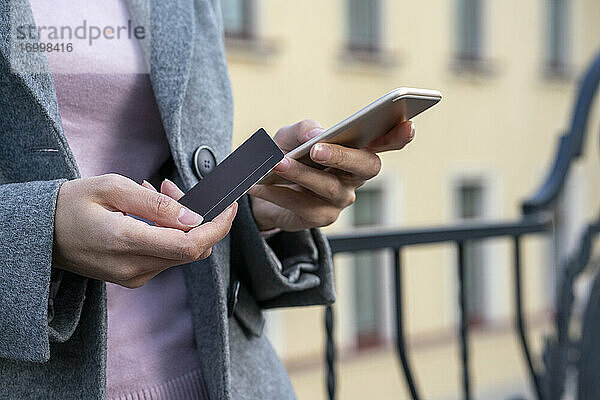 Geschäftsfrau mit Kreditkarte beim Bezahlen mit dem Mobiltelefon