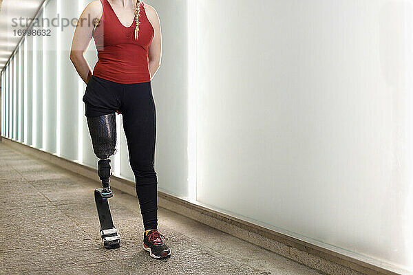 Sportlerin mit Beinprothese  die in einer Unterführung an einer Mauer vorbeiläuft