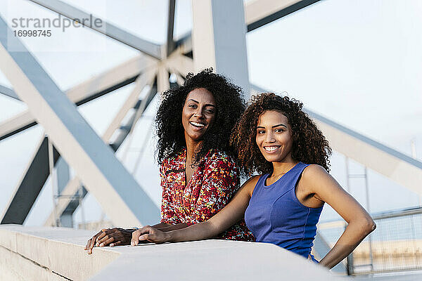 Lächelnde Freundinnen stehen auf einer Brücke