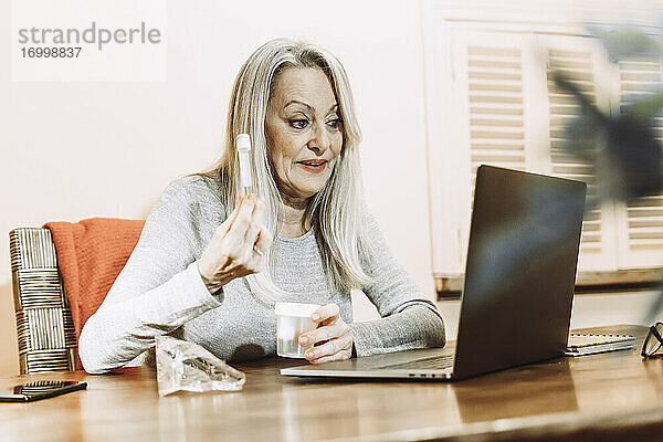 Ältere Frau  die über medizinische Proben diskutiert  während sie zu Hause eine Online-Konsultation durchführt