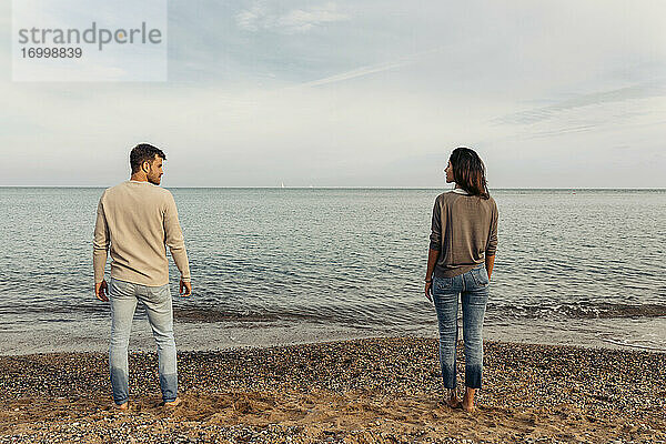 Junges Paar steht auf Sand gegen den Himmel am Strand