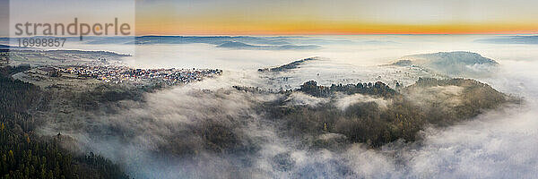 Deutschland  Baden-Württemberg  Berglen  Drohnenansicht eines in dichten Nebel gehüllten Dorfes in der Morgendämmerung