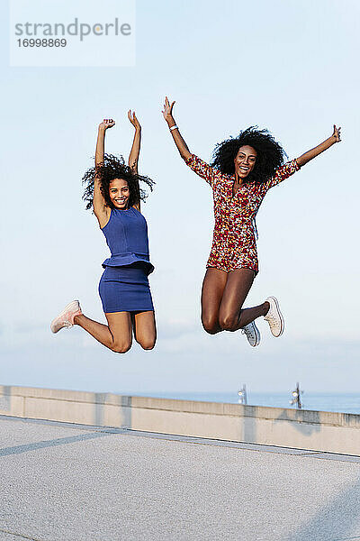 Fröhliche Freundinnen springen auf dem Dach eines Gebäudes
