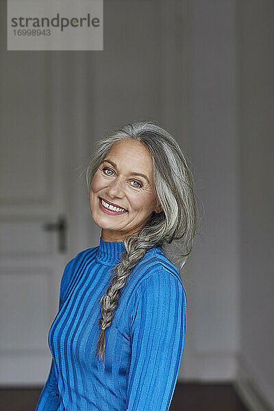 Lächelnde reife Frau mit grauem Haar zu Hause
