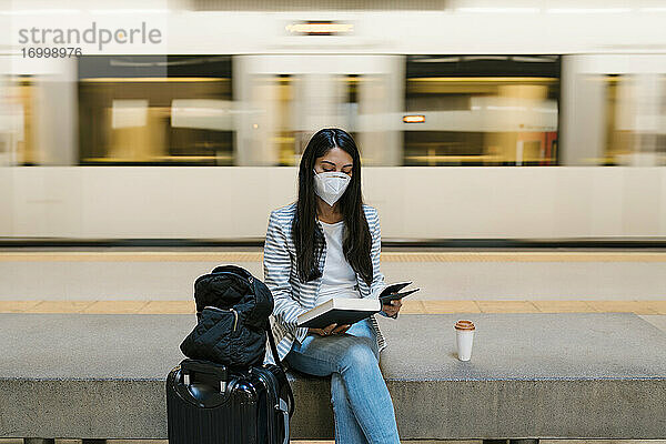 Frau liest ein Buch  während sie in der U-Bahn-Station gegen einen fahrenden Zug sitzt