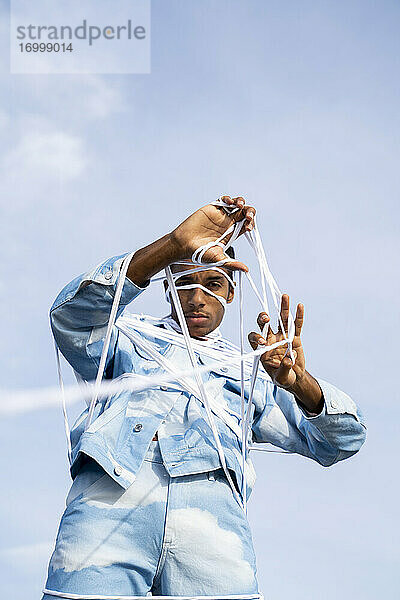 Gefangener junger Mann entfernt Seil  während er gegen den Himmel steht