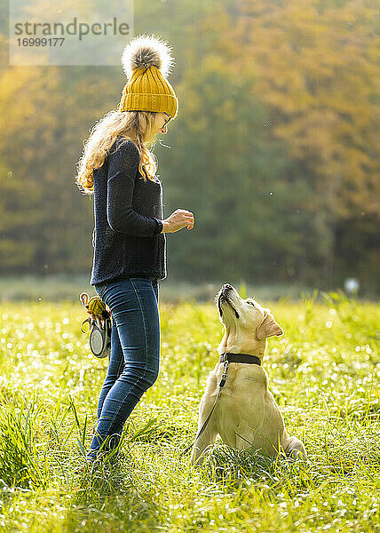 Junge Frau steht mit Labrador Retriever im Park