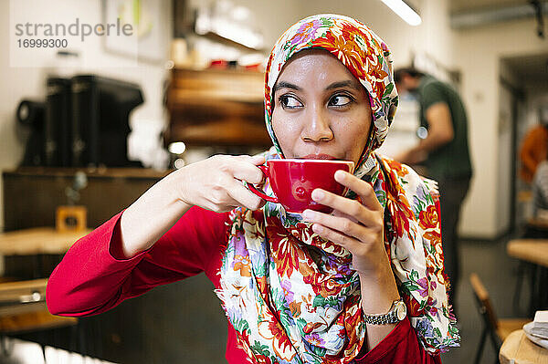 Malaysische Frau schaut beim Kaffeetrinken im Café weg