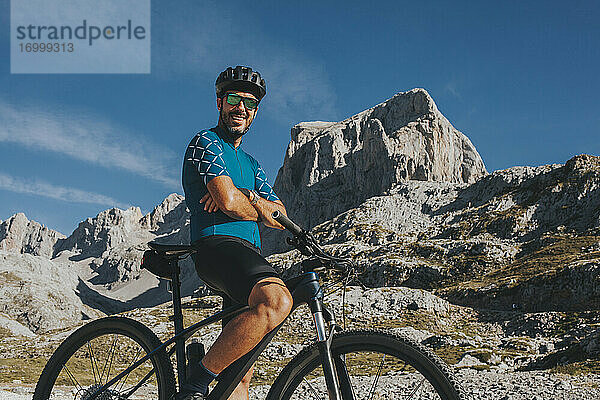 Lächelnder Mountainbiker mit verschränkten Armen im Nationalpark Picos de Europa in Kantabrien  Spanien