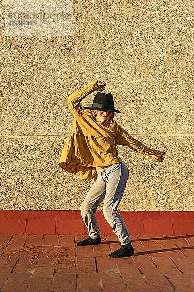 Mädchen mit übergroßem Hut tanzt auf einer Wurzelterrasse