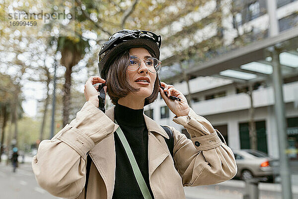 Mittlere erwachsene Frau trägt einen Fahrradhelm  während sie auf der Straße in der Stadt steht