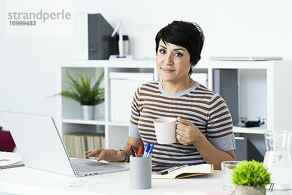 Porträt einer Geschäftsfrau mit Laptop am Bürotisch