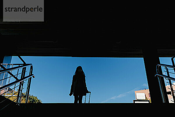 Silhouette einer Frau mit Gepäck in einer U-Bahn-Station