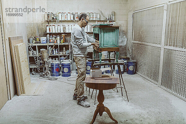 Handwerker bei der Arbeit an antiken Möbeln im Stehen in der Werkstatt