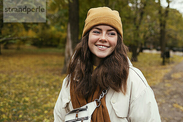 Lächelnde junge Frau  die im herbstlichen Park wegschaut