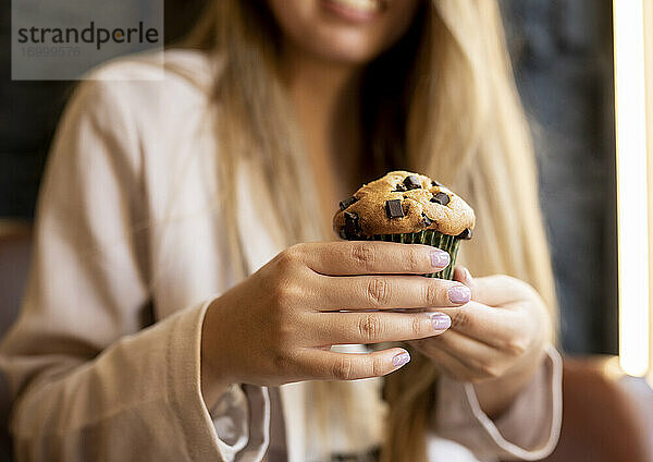 Frau hält Schokoladenmuffin  während sie im Café sitzt