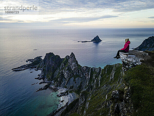 Frau sitzt und bewundert die Aussicht auf Matind  Andoya  Norwegen