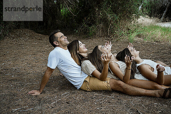 Fröhliche Familie macht Yoga  während sie im Urlaub im Wald in einer Reihe liegt