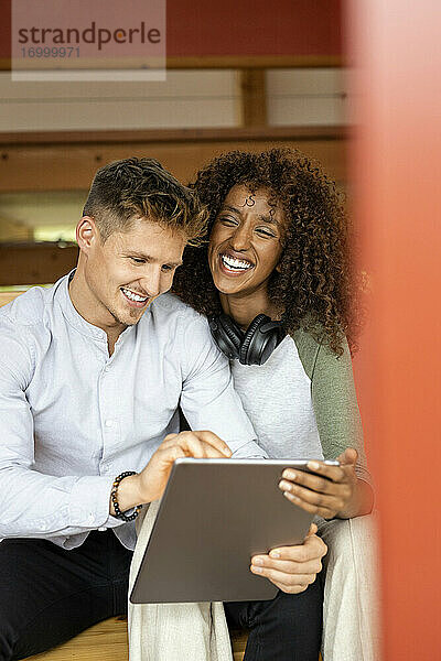 Lächelndes Paar  das ein digitales Tablet benutzt  während es zu Hause sitzt