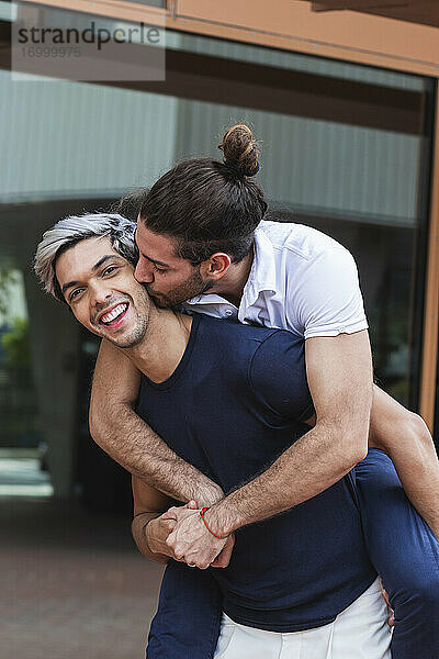 Lächelnder Mann nimmt schwulen Partner in der Stadt huckepack