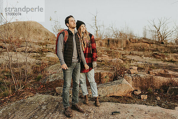 Junges Paar steht zusammen und bewundert die umliegende Landschaft während einer Herbstwanderung