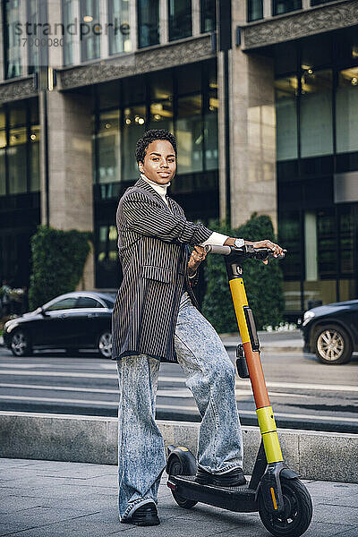 Selbstbewusste Geschäftsfrau mit Elektro-Scooter auf der Straße in der Stadt