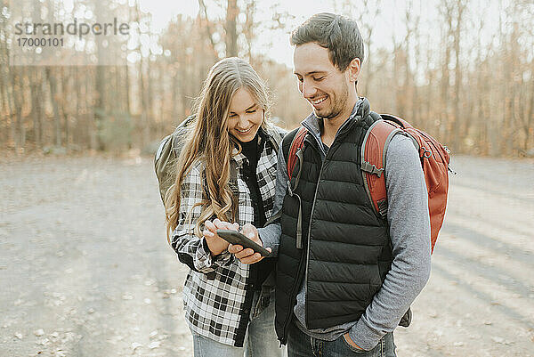 Junges Paar benutzt Smartphone bei Herbstwanderung