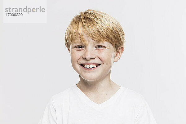 Fröhlicher süßer Junge mit blondem Haar vor weißem Hintergrund