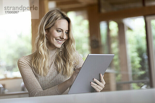 Junge Frau benutzt ein digitales Tablet  während sie zu Hause sitzt