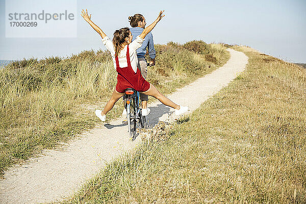 Unbekümmerte Freundin genießt Fahrradtour mit Freund an einem sonnigen Tag