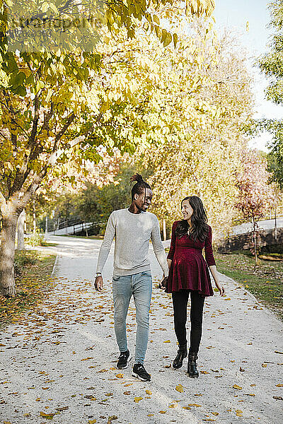Glückliches Paar hält sich beim Spaziergang im Park an den Händen