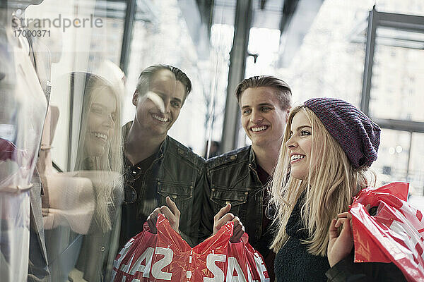 Paar mit Einkaufstasche lächelnd beim Betrachten des Schaufensters