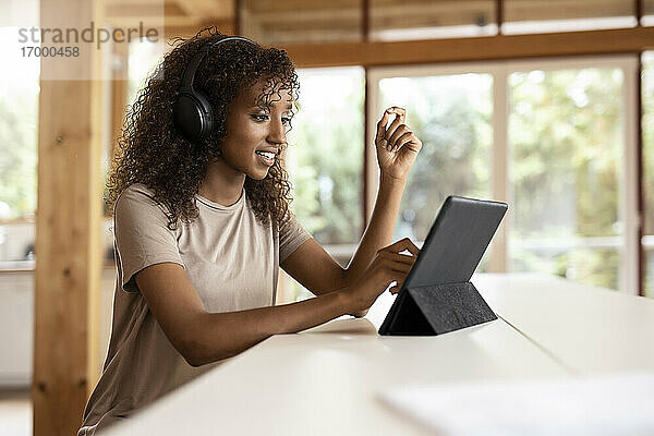 Geschäftsfrau mit Kopfhörern und digitalem Tablet  während sie zu Hause sitzt