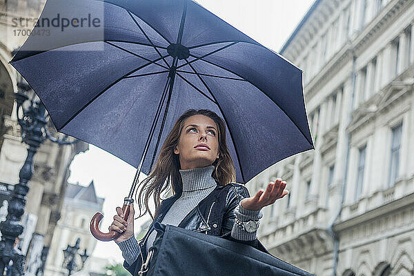 Geschäftsfrau  die während der Regenzeit in der Stadt unter einem Regenschirm wegschaut