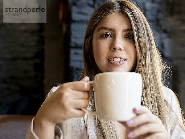 Junge Frau trinkt Kaffee  während sie im Cafe sitzt