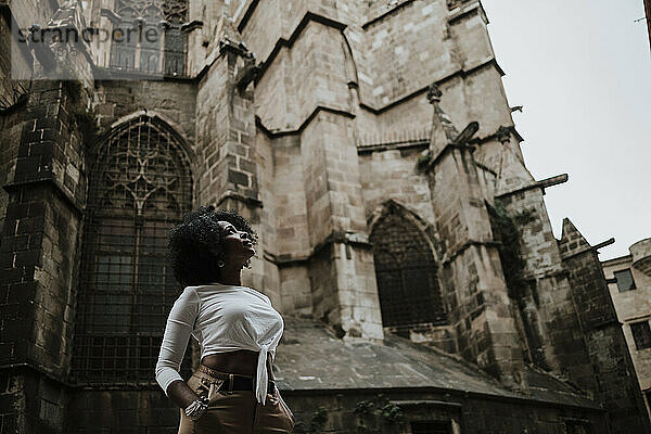 Nachdenkliche Frau  die nach oben schaut  während sie vor der Kathedrale von Barcelona steht  Barcelona  Spanien