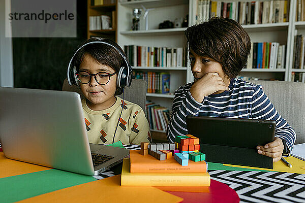 Junge im Vorschulalter schaut beim E-Learning mit einem männlichen Freund auf den Laptop