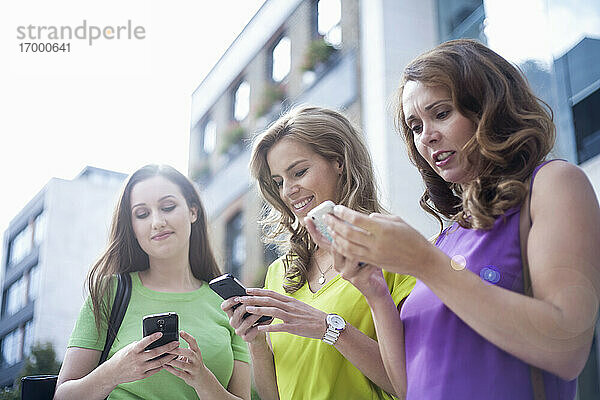 Geschäftsfrauen  die in der Pause außerhalb des Büros SMS schreiben
